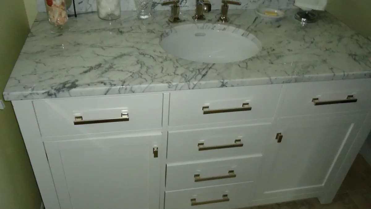 A white bathroom vanity that combines drawers and cabinet doors, in a New Jersey condominium. Photo: Tomwsulcer / Wikimedia Commons, CC0