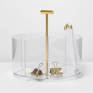 Clear round acrylic organizer with a gold-tone T-handle, holding white pencils and gold binder clips