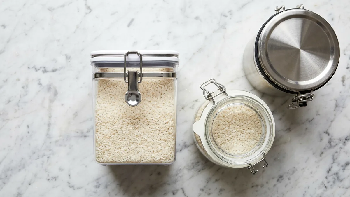 Flat lay of different types of food storage containers for rice including plastic, glass, and stainless steel options