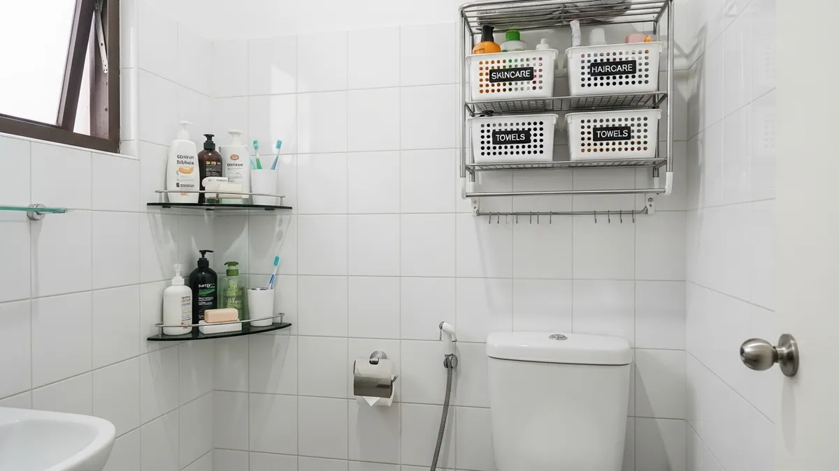 Bathroom home storage solutions with corner shelf and over-toilet rack in small Indonesian bathroom