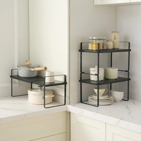 Black steel expandable shelves set up in a white kitchen corner holding a pot, small bowls and kitchen items on two levels. Photo: Sesoris product catalog